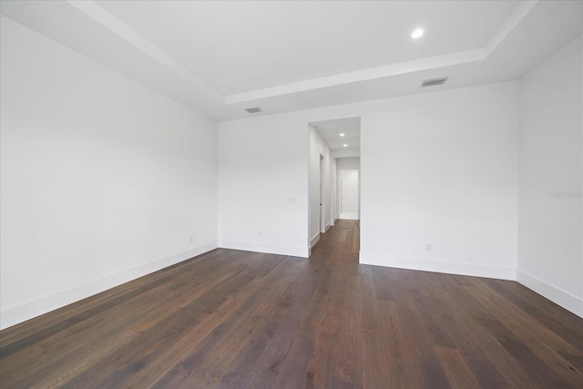 spare room featuring dark wood-type flooring and a tray ceiling