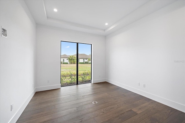 spare room with dark wood-type flooring and a raised ceiling