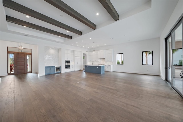 unfurnished living room with sink, dark hardwood / wood-style floors, and beamed ceiling