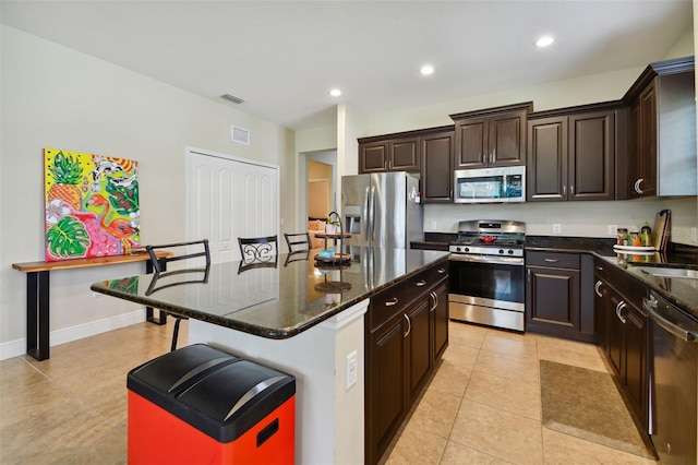 4618 Deep Creek Ter, Parrish, FL 34219 - kitchen with light tile flooring, dark brown cabinetry, a center island, and appliances with stainless steel finishes