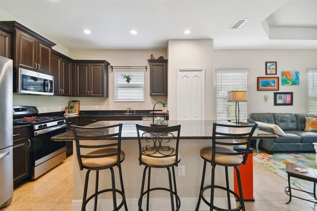 4618 Deep Creek Ter, Parrish, FL 34219 - kitchen with a kitchen island, appliances with stainless steel finishes, a breakfast bar, light tile flooring, and a wealth of natural light