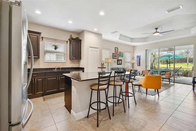 4618 Deep Creek Ter, Parrish, FL 34219 - kitchen featuring refrigerator with ice dispenser, ceiling fan, a kitchen island, a breakfast bar area, and a tray ceiling