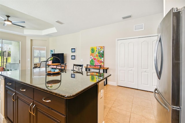 4618 Deep Creek Ter, Parrish, FL 34219 - kitchen featuring a tray ceiling, ceiling fan, stainless steel fridge, dark stone countertops, and a kitchen island