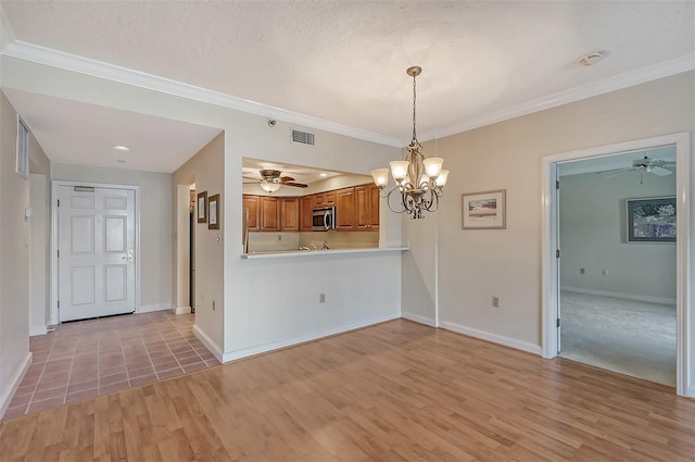 unfurnished dining area with light colored carpet, ornamental molding, and ceiling fan with notable chandelier