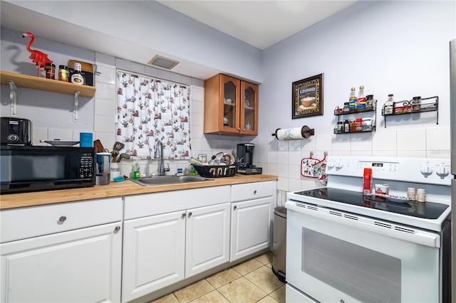 kitchen featuring sink, light tile floors, white electric stove, backsplash, and white cabinetry