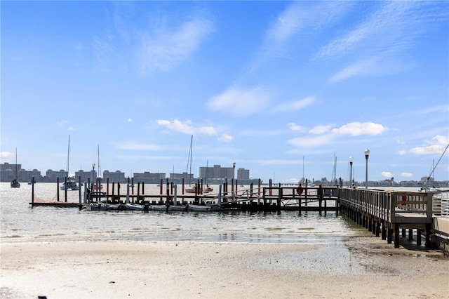 view of dock with a beach view and a water view