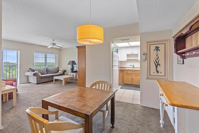 dining room with light carpet, ceiling fan, a textured ceiling, and sink