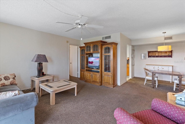 living room with dark carpet, ceiling fan, and a textured ceiling