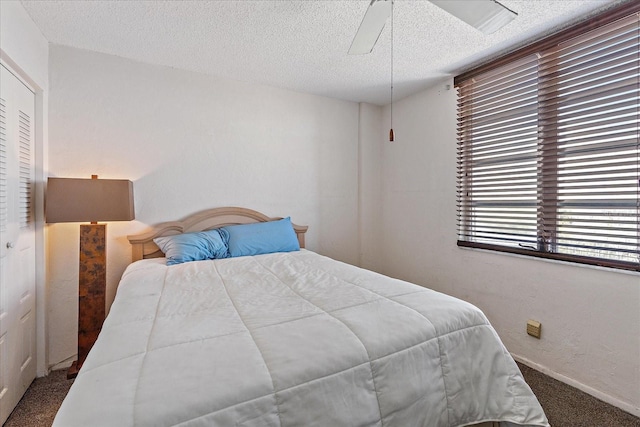 carpeted bedroom featuring ceiling fan and a textured ceiling