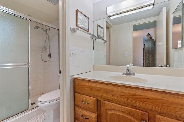 bathroom with an enclosed shower, tile flooring, a textured ceiling, vanity with extensive cabinet space, and toilet