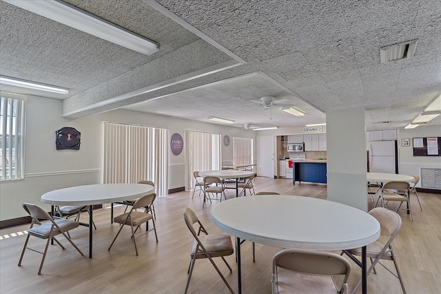 dining room with light hardwood / wood-style flooring, ceiling fan, and a textured ceiling