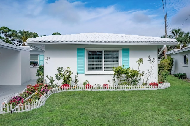 view of front of house featuring a tile roof, a front lawn, and stucco siding