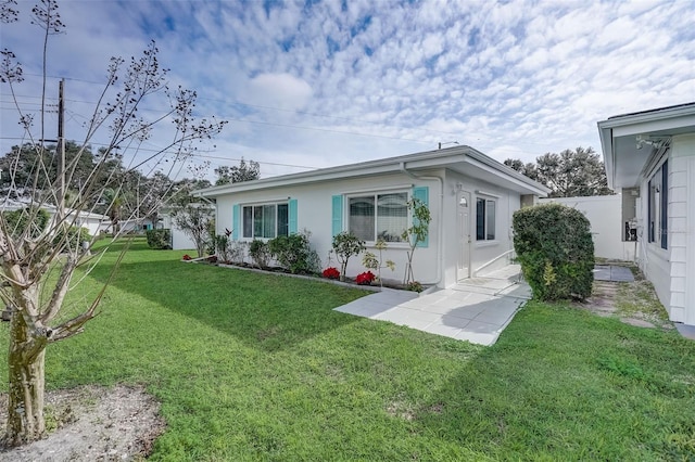 back of house with a lawn, fence, and stucco siding