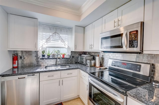 kitchen featuring stainless steel appliances, sink, backsplash, and white cabinetry