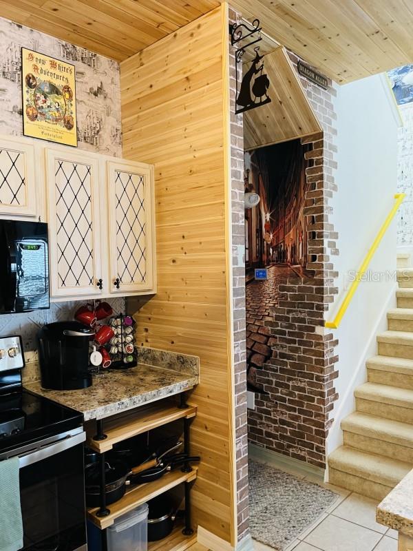 kitchen featuring a skylight, electric range, light tile flooring, wood walls, and wood ceiling