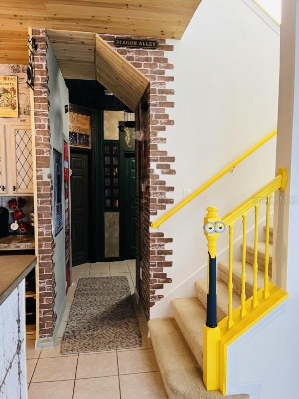 interior space featuring brick wall, light tile flooring, and wooden ceiling