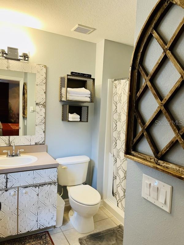 bathroom featuring a textured ceiling, tile floors, large vanity, and toilet