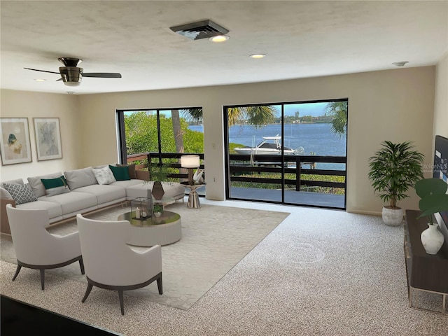 living room featuring light colored carpet, ceiling fan, and a water view