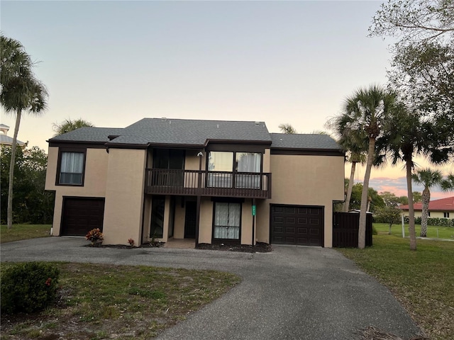 view of front of house with a balcony, a yard, and a garage