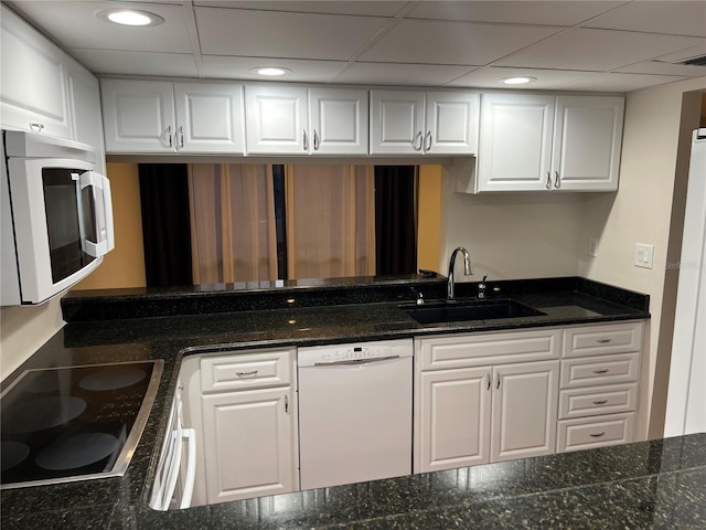 kitchen with white cabinetry, white appliances, sink, a paneled ceiling, and dark stone countertops