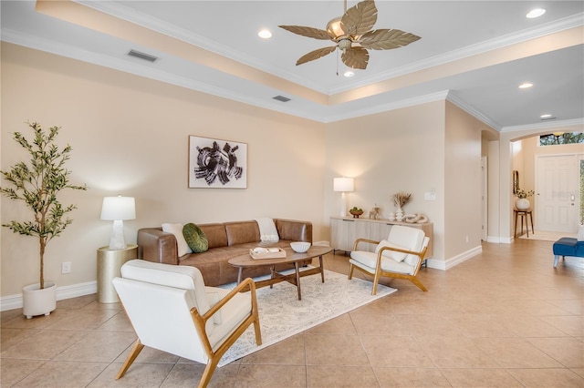 living room featuring light tile patterned flooring, ornamental molding, and a tray ceiling