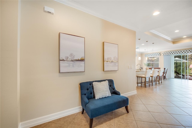 living area featuring a raised ceiling, sink, light tile patterned floors, and ornamental molding