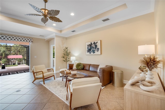 living room with light tile patterned floors, a raised ceiling, ceiling fan, and ornamental molding