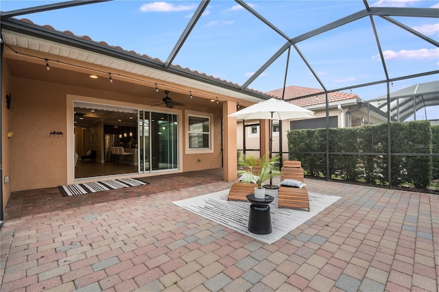 view of patio with glass enclosure and ceiling fan