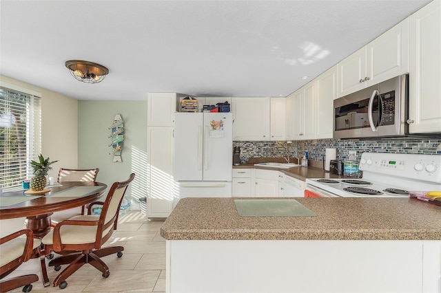 kitchen with backsplash, light tile floors, white cabinets, stove, and white refrigerator