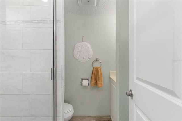 bathroom with a shower with door, a textured ceiling, and toilet