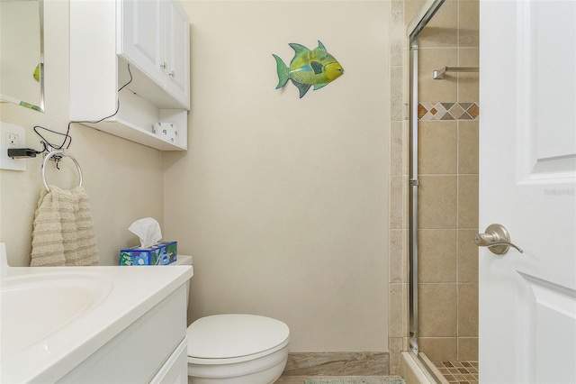 bathroom with toilet, vanity, and a shower with shower door