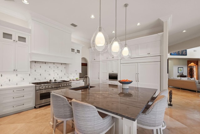 kitchen with sink, white cabinets, high quality appliances, and a spacious island