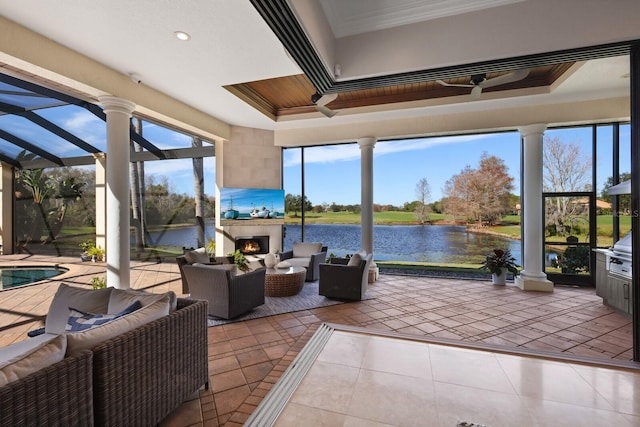 sunroom / solarium featuring exterior fireplace, a tray ceiling, and a water view