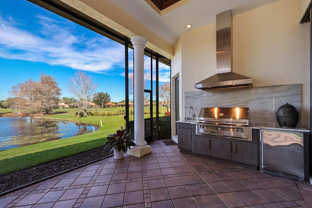 view of patio / terrace featuring a water view, an outdoor kitchen, area for grilling, and sink