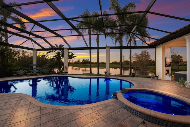 pool at dusk featuring a water view, an in ground hot tub, a lanai, and a patio