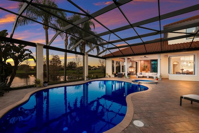 pool at dusk with an in ground hot tub, a lanai, and a patio area