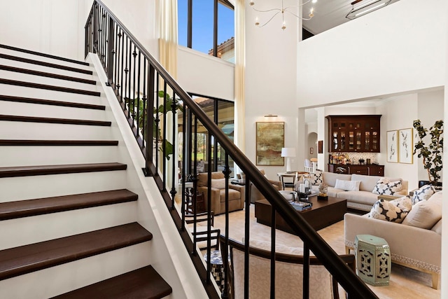 stairs featuring an inviting chandelier and a towering ceiling