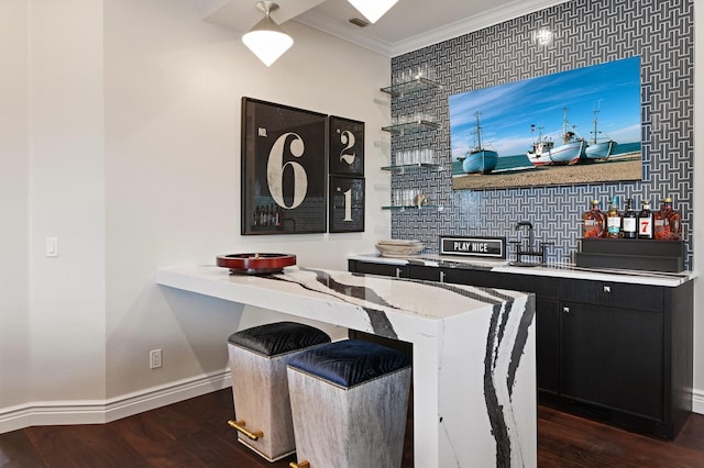 kitchen featuring crown molding, a kitchen bar, dark hardwood / wood-style flooring, and decorative backsplash