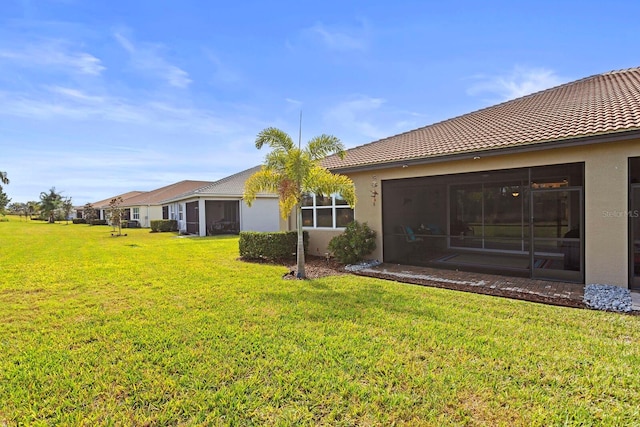 rear view of house with a yard and a sunroom