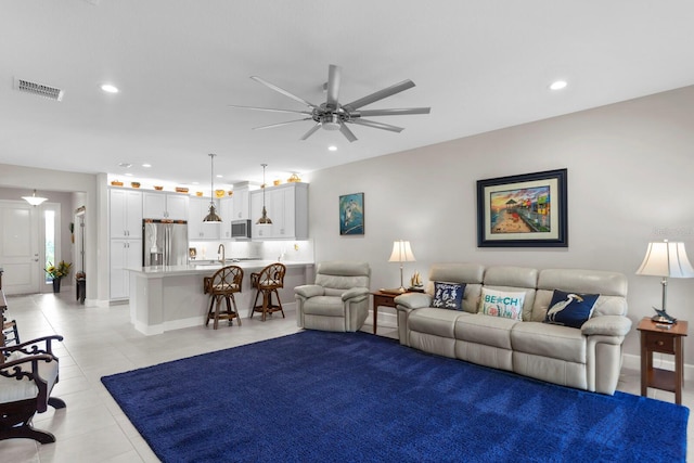 living room featuring ceiling fan, sink, and light tile patterned floors