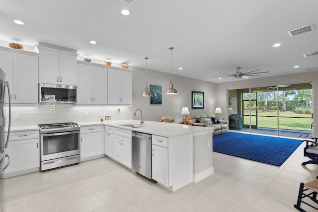 kitchen with hanging light fixtures, white cabinets, kitchen peninsula, stainless steel appliances, and sink