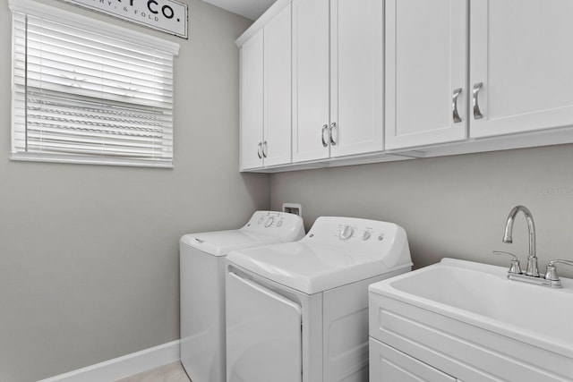 clothes washing area with cabinets, washer and dryer, and sink