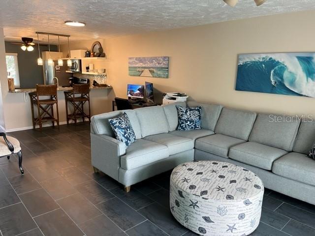 living room with ceiling fan and a textured ceiling