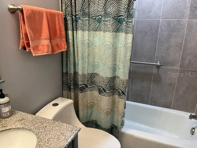 full bathroom with vanity, shower / bathtub combination with curtain, and toilet