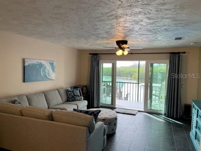 living room featuring ceiling fan and a textured ceiling