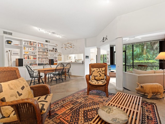 tiled living room with a notable chandelier and track lighting