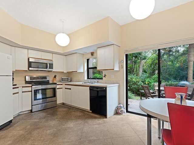 kitchen with white cabinets, hanging light fixtures, stainless steel appliances, and light tile floors