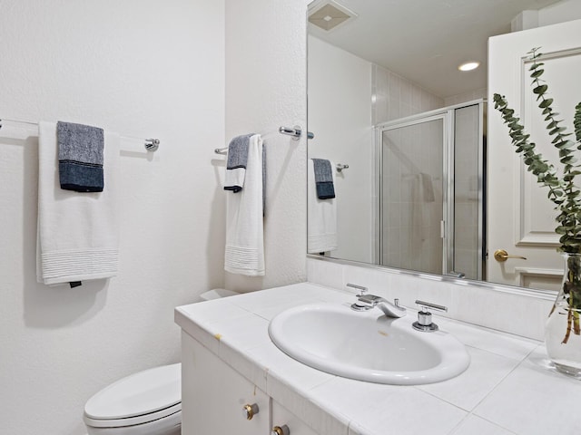 bathroom featuring vanity, toilet, and a shower with shower door