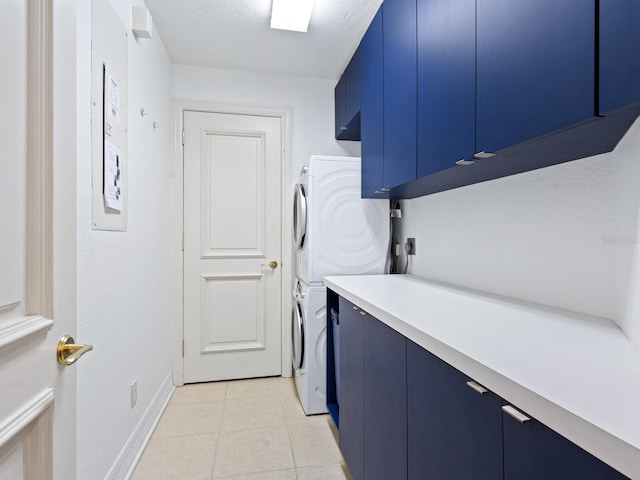 laundry area with light tile patterned flooring, cabinets, and stacked washer and dryer