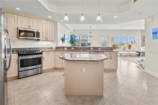 kitchen with stainless steel appliances, decorative light fixtures, light stone countertops, kitchen peninsula, and a tray ceiling